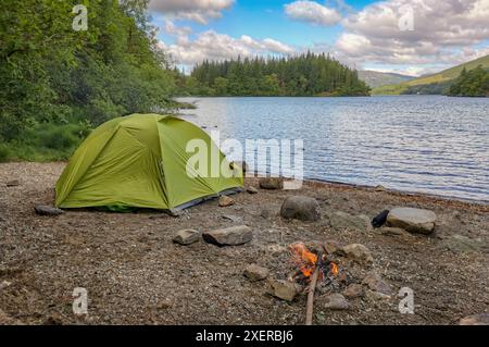 Green Zelt Wildcamping neben dem Lagerfeuer am Ufer des Loch Ard, einem See umgeben von Wald und Hügeln in Loch Lomond und dem Trossachs National Par Stockfoto