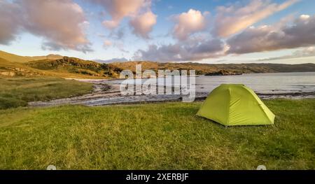 Grünes Zelt wildes Camping auf Gras am Peanmeanach Beach, an der Westküste Schottlands, mit Sonne und Wolken am Himmel Stockfoto