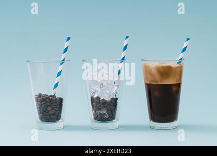 Kreatives Layout mit drei Glasbechern, gerösteten Kaffeebohnen, Eiswürfeln, Eiskaffee und Trinkhalmen aus Papier auf pastellblauem Hintergrund. Stockfoto