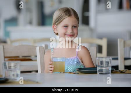 Ein entzückendes kleines Mädchen, das im Restaurant Saft trinkt Stockfoto