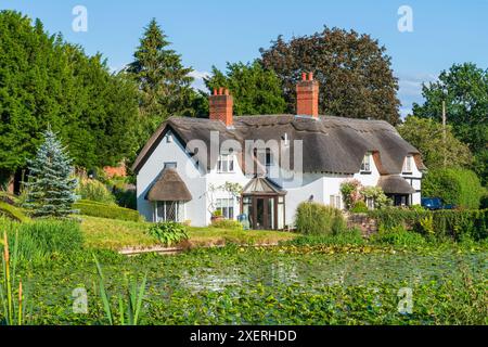 Wunderschönes englisches Reetdachhaus in Shropshire, Großbritannien mit einem See und einem Lilienteich im Vordergrund Stockfoto