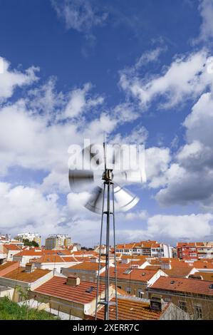 Die Windmühle steht hoch über den Dächern von lissabon und steht im Kontrast zu den modernen Gebäuden und traditionellen roten Dächern der Stadt Stockfoto