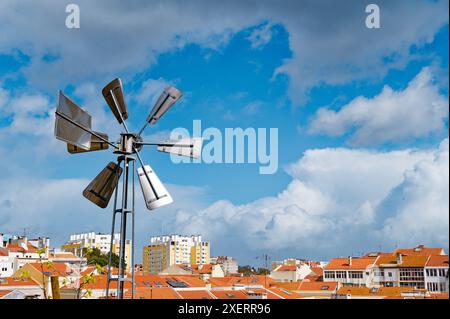 Die Windmühle steht hoch über den Dächern von lissabon und steht im Kontrast zu den modernen Gebäuden und traditionellen roten Dächern der Stadt Stockfoto