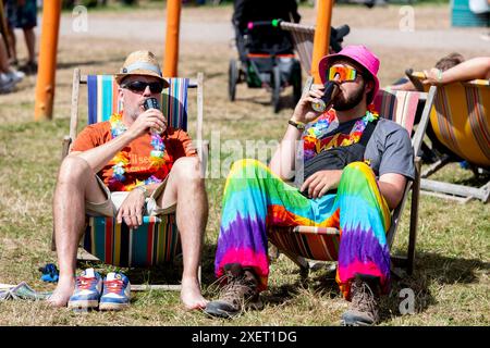 Glastonbury, Großbritannien. Tag 4, 29. Juni 2024. Festivalbesucher in farbenfrohen, schicken Kleidern sitzen im Glastonbury Festival, Worthy Farm in Somerset. Bilddatum: Samstag, 29. Juni 2024. Das Foto sollte lauten: David Jensen / Alamy Live News Stockfoto