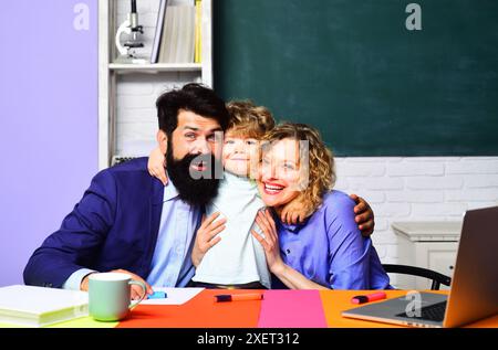 Erster Schultag. Ein lächelnder Schuljunge umarmt die Lehrer im Klassenzimmer. Bildung, Nachhilfe und Lernen für Kinder. Grundschüler Junge e Stockfoto