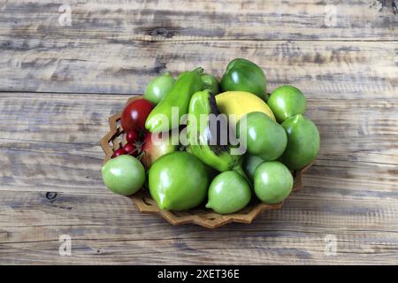 Stillleben von Gemüse auf einer Holzplatte - Tomaten, grün und rot, bulgarische grüne Paprika, reife Äpfel. Stockfoto