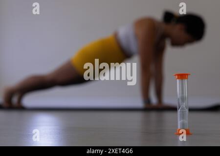 Nahaufnahme von Sanduhr und verschwommener Frau in Plankenstellung Stockfoto