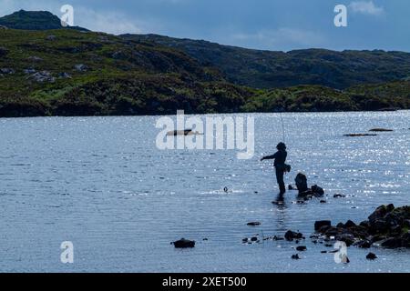 Ein Fliegenfischer spielt einen Fisch in den abgelegenen Hügeln von Assynt, Schottland Stockfoto