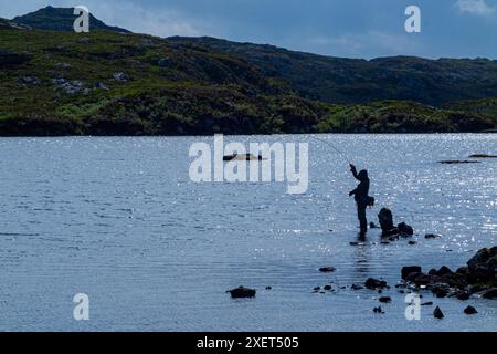 Ein Fliegenfischer spielt einen Fisch in den abgelegenen Hügeln von Assynt, Schottland Stockfoto