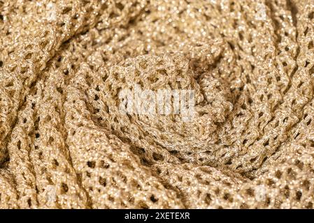 Gedrehtes Strickmaterial mit Plisseedetail und goldenem Garn Stockfoto