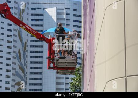 Wien, Österreich, Österreich. Juni 2024. Der australische Künstler FINTAN MAGEE verleiht seinem Porträt „Frau mit Taube – Shaping Our Common Future“ den letzten Schliff. Das größte Wandgemälde Wiens ist 50 Meter hoch und 20 Meter breit, und die U-Bahn U2 fährt jeden Tag vorbei und macht es für das Massenpublikum sichtbar. (Kreditbild: © Bianca Otero/ZUMA Press Wire) NUR REDAKTIONELLE VERWENDUNG! Nicht für kommerzielle ZWECKE! Stockfoto