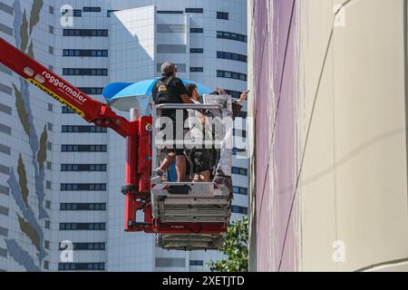 Wien, Österreich, Österreich. Juni 2024. Der australische Künstler FINTAN MAGEE verleiht seinem Porträt „Frau mit Taube – Shaping Our Common Future“ den letzten Schliff. Das größte Wandgemälde Wiens ist 50 Meter hoch und 20 Meter breit, und die U-Bahn U2 fährt jeden Tag vorbei und macht es für das Massenpublikum sichtbar. (Kreditbild: © Bianca Otero/ZUMA Press Wire) NUR REDAKTIONELLE VERWENDUNG! Nicht für kommerzielle ZWECKE! Stockfoto