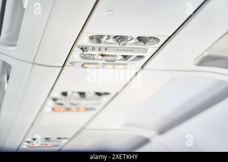 Selektiver Fokus auf die Decke eines Passagierflugzeugs, wo sich Sicherheitselemente, Tasten und Schalter wie eine Sauerstoffmaske befinden. Mit Platz zum Kopieren. Hochwertige Fotos Stockfoto