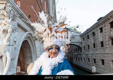 Karneval in Venedig, Mann mit ausgeklügeltem Kopfschmuck und Federn, der auf der Seufzerbrücke in Venedig posiert Stockfoto