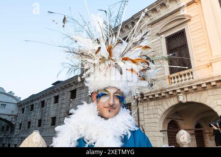 Karneval in Venedig, Mann mit ausgeklügeltem Kopfschmuck und Federn, der auf der Seufzerbrücke in Venedig posiert Stockfoto