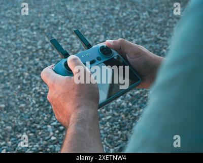 Ein über die Schulter geschossener Schuss von den Händen eines Mannes, der einen Drohnen-Fernbedienungs-Joystick hält. Stockfoto