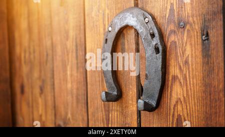 Ein Hufeisen für Glück hängt an einer Holztür. Symbol für Glück und Glück. Ein eisernes Glückshufeisen - ein Talisman-Aberglaube für Glück. Stockfoto