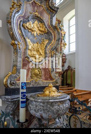 Schwyz, Schweiz - 18. Juni 2024: Taufstein und Osterkerze in der Pfarrkirche St. Martin, einer spätbarocken Hallenkirche Stockfoto