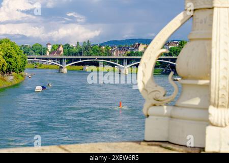 Basler Stadt - Eine Brücke überspannt den Rhein mit einer Stadt im Hintergrund. Die Brücke ist ein Steinbauwerk mit einem rot-weißen Schild. Die Stadt ist Fil Stockfoto