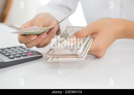 Eine Frau hält einen Stapel Rechnungen und einen Taschenrechner. Sie berechnet wahrscheinlich ihre Ausgaben oder ihr Budget Stockfoto