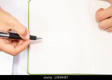 Nahaufnahme einer nicht erkennbaren Frau, die am Schreibtisch in Notizbuch schreibt Stockfoto