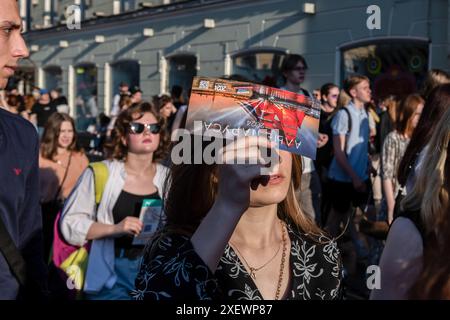 St. Petersburg, Russland. Juni 2024. Ein Mädchen hat ein Ticket für die „Scarlet Sails“-Feier, während es in der Schlange steht. Die traditionelle Abschlussfeier des Scarlet Sail fand am Palastplatz und am Ufer des Flusses Neva in St. Petersburg statt. Ein Konzert mit russischen Popstars fand auf dem Palastplatz statt. Das Hauptsymbol der Feier, ein Schiff mit scharlachroten Segeln aus Alexander Grins gleichnamigem Roman, segelte entlang der Neva unter den Zugbrücken, wo es von den Absolventen der St. Petersburger Schule begrüßt wurde. Quelle: SOPA Images Limited/Alamy Live News Stockfoto