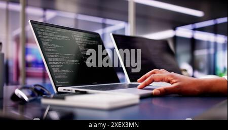 Multi-Tasking-Website der afroamerikanischen Frau Coding auf Laptop am Schreibtisch, während Musik vom Bildschirm gehört wird Stockfoto