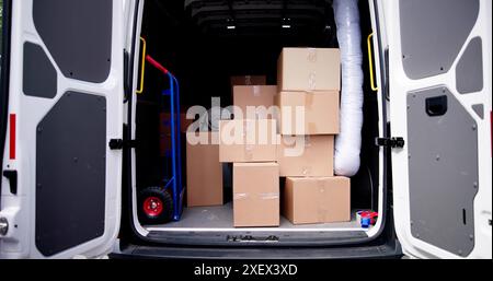 Professional Movers liefern verpackte Kartons vom Business Relocation Service mit White Van auf der Urban Street für die Lieferung von Büromöbeln. Stockfoto