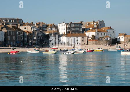 Harbour, St. Ives, Cornwall, Großbritannien – Häuser säumen den Hafen, in dem mehrere Boote festgemacht sind. Stockfoto