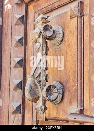 Alter schmiedeeiserner Türknauf an einer Holztür. Stockfoto