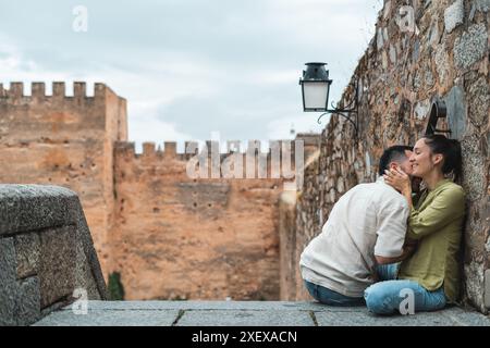 Ein Paar küsst sich vor einem Schloss. Die Frau trägt ein grünes Hemd Stockfoto