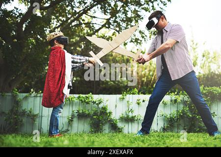 Vater, Sohn und Spiel mit Schwert kämpfen um Bindung oder VR in Kostüm, Cosplay oder Hinterhof zu Hause. Lustiger Vater, Kind oder kleiner Junge, der Outdoor-Spiele genießt Stockfoto