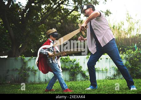 Vater, Sohn und Spiel mit Schwert für Kampf, VR oder Bonding in Kostüm Cosplay oder Hinterhof zu Hause. Lustiger Vater, Kind oder kleiner Junge, der Outdoor-Spiele genießt Stockfoto