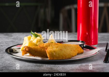 Frittiertes, beschichtetes Fischfilet mit Kartoffelsalat auf Steintisch Stockfoto