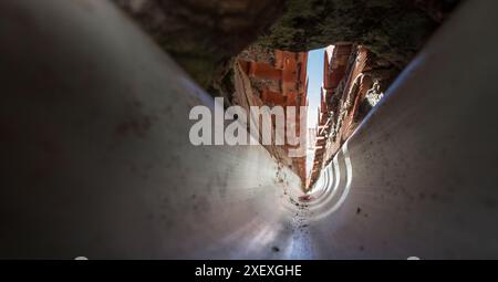 Innenraum einer PVC-Dachrinne am Zusammenfluss eines Giebeldaches. Tunnelsicht Stockfoto