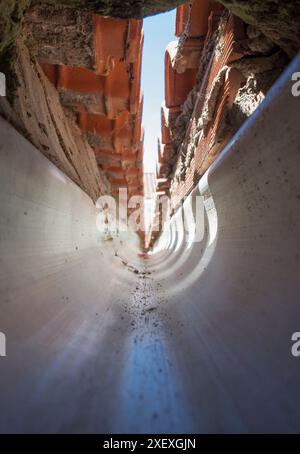 Innenraum einer PVC-Dachrinne am Zusammenfluss eines Giebeldaches. Tunnelsicht Stockfoto