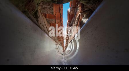 Innenraum einer PVC-Dachrinne am Zusammenfluss eines Giebeldaches. Tunnelsicht Stockfoto