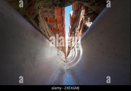 Innenraum einer PVC-Dachrinne am Zusammenfluss eines Giebeldaches. Tunnelsicht Stockfoto