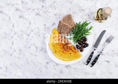 Gebratenes Omelette mit Zwiebeln, Kräutern und Oliven. Leckeres Frühstück mit Eiern und Toast Stockfoto