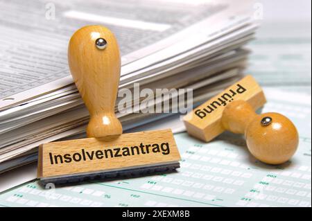 Insolvenzantrag an einem Papierstapel lehnt ein Holzstempel mit dem Aufdruck: Insolvenzantrag und Prüfung *** Insolvenzantrag mit Holzstempel Stockfoto