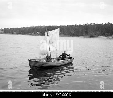 Zwei Jungs in einem selbstgebauten Segelboot im Jahr 1950. Zwei leichte Segel sind im Mast, der ein dünnerer Baumstamm ist, gehisst. Einfacher und kreativer Einfallsreichtum der Jungen 1950. Kristoffersson Ref. 15K-24 Stockfoto