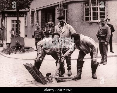 Der Nazi-Putsch in Wien (Juli-Putsch) und die Ermordung von Bundeskanzler Engelbert Dollfuss. Österreich, 1934 bewaffnete Mitglieder der heimwehr steigen in die Kanalisation ab. Einer von ihnen hält eine Spitzhacke und eine Erma EMP-35 Maschinenpistole. Im Hintergrund links befindet sich ein schweres Maschinengewehr mit Schutzschild. Stockfoto