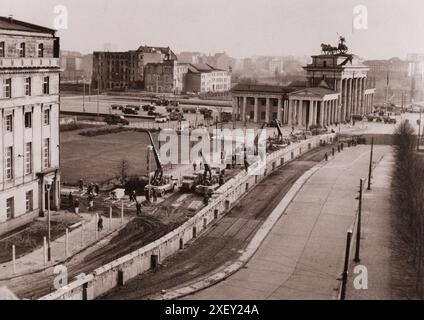 Vintage-Foto der Berliner Krise von 1961: Bau der Berliner Mauer verstärkt. Unter dem wachsamen Auge der kommunistischen Polizei verstärken ostdeutsche Arbeiter in der Nähe des Brandenburger Tors die Stadtmauer. Seit der Errichtung der Mauer am 13. August 1961, um den Einzug der Ostdeutschen nach West-Berlin zu stoppen, haben die Ostdeutschen Kommunisten Bunker, Scheinwerfer, Schieß- und Beobachtungsposten hinzugefügt. Oktober 1961 Stockfoto