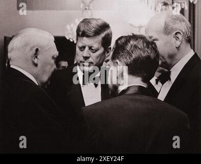 Vintage-Foto der Berliner Krise von 1961: Mauerbau. Vizekanzler Ludwig Erhard (links) spricht mit Präsident Kennedy und US-Außenminister Dean Rusk (rechts) bei einem Abendessen von Bundeskanzler Konrad Adenauer. Robert H. Lochner, Direktor von RIAS, dem US-Radiosender in West-Berlin (zurück zur Kamera), fungiert als Dolmetscher. Bundesrepublik Deutschland. Juni 1963 Stockfoto