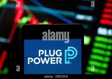 China. Juni 2024. In dieser Fotoabbildung hat das amerikanische Unternehmen Wasserstoff-Brennstoffzellensysteme entwickelt, die herkömmliche Batterien in Geräten ersetzen, Power Plug (NASDAQ: PLUG), Logo auf einem Smartphone mit einem wirtschaftlichen Börsenindex im Hintergrund. Quelle: SOPA Images Limited/Alamy Live News Stockfoto
