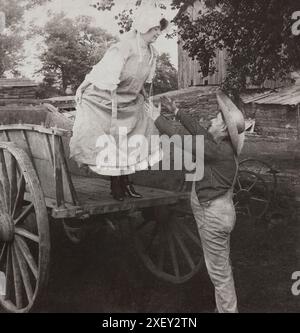 Vintage-Foto von Verliebten. „Catch Me Tom!“. USA. 1906 Frau, die kurz vor dem Sprung vom Wagen in die Arme eines Bauern steht. Stockfoto