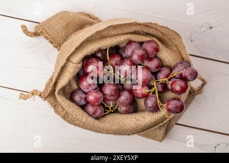 Reife Trauben in einem Jutebeutel auf einem Holztisch, Makro, Draufsicht. Stockfoto