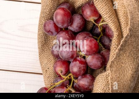 Reife Trauben in einem Jutebeutel auf einem Holztisch, Makro, Draufsicht. Stockfoto