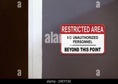 Rot-weißes Schild mit eingeschränktem Bereich an der Seite einer offenen Tür mit der Aufschrift: Eingeschränkter Bereich, keine unbefugten Personen über diesen Punkt hinaus. Stockfoto