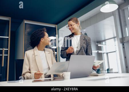 Zwei weibliche Kollegen diskutieren das Projekt, bevor sie der Teamleiterin im Büro eine Präsentation zeigen Stockfoto